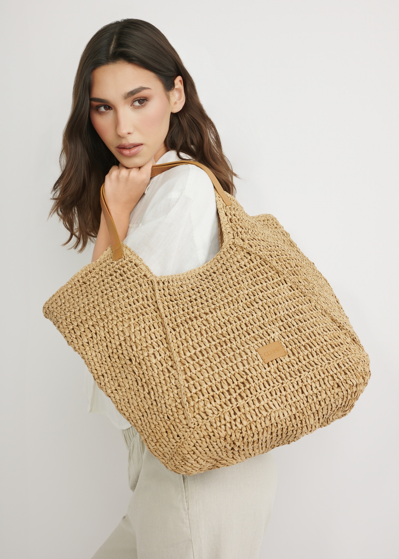 Beżowa słomkowa torebka shopper TOREC-1223-1E(W26) - widok produktu z przodu, na modelce, na jasnym tle. 