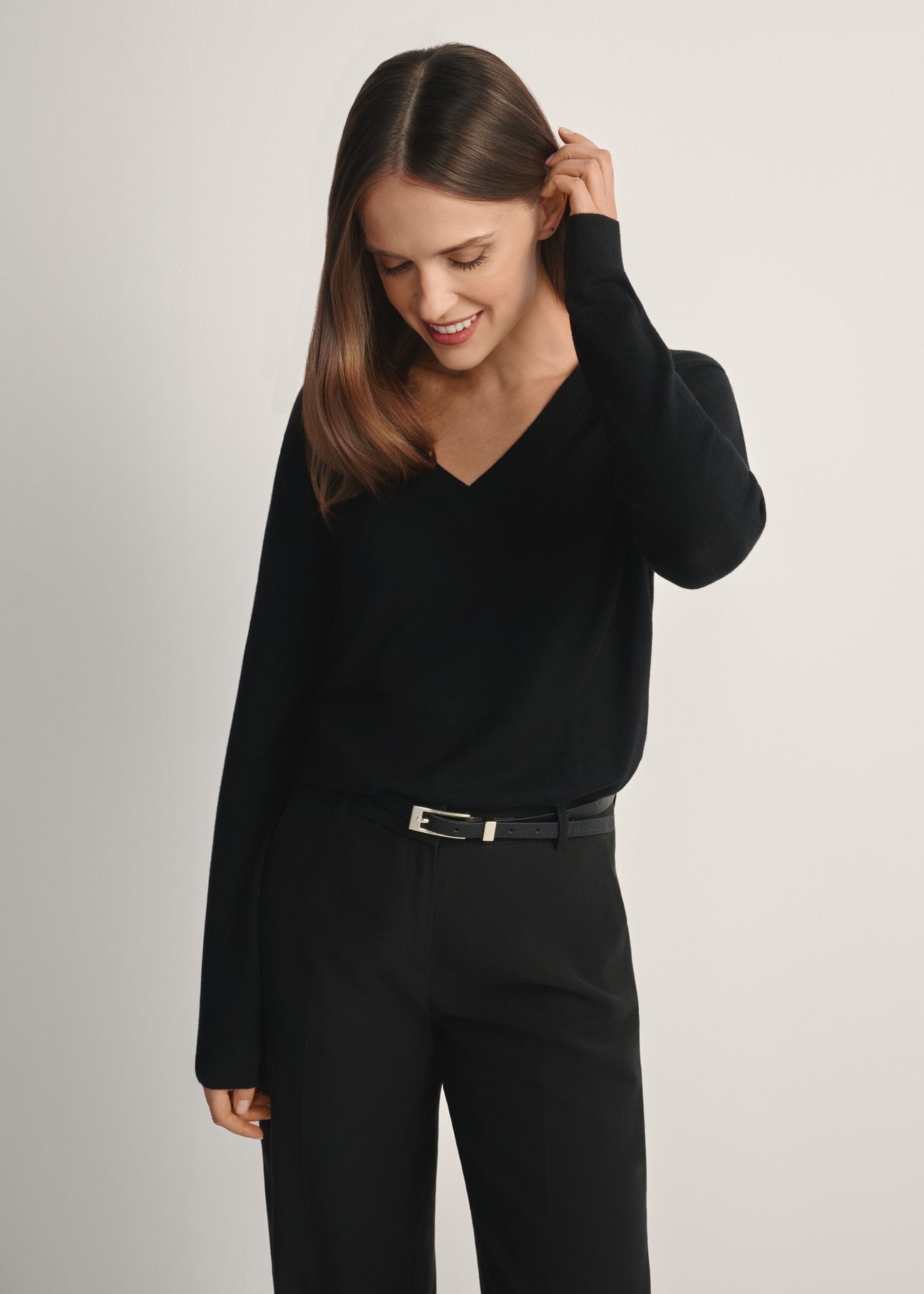 Czarny sweter z dekoltem V-neck SWEDT-0201-99(W24), widok produktu od przodu na modelce, widoczna połowa sylwetki.