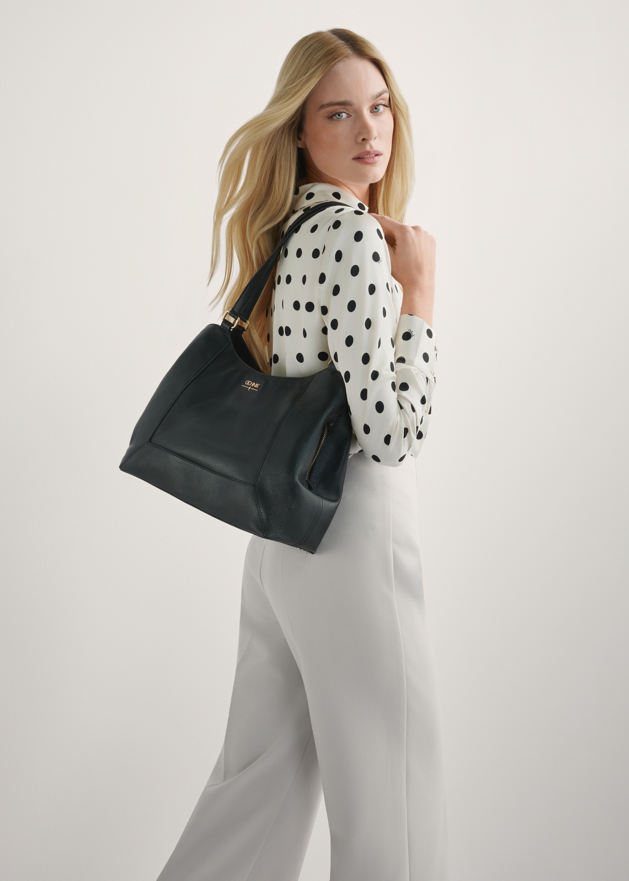 Czarna skórzana torebka shopper damska TORES-1264-9I(W26), widok produktu na ramieniu modelki. Widoczna połowa sylwetki.