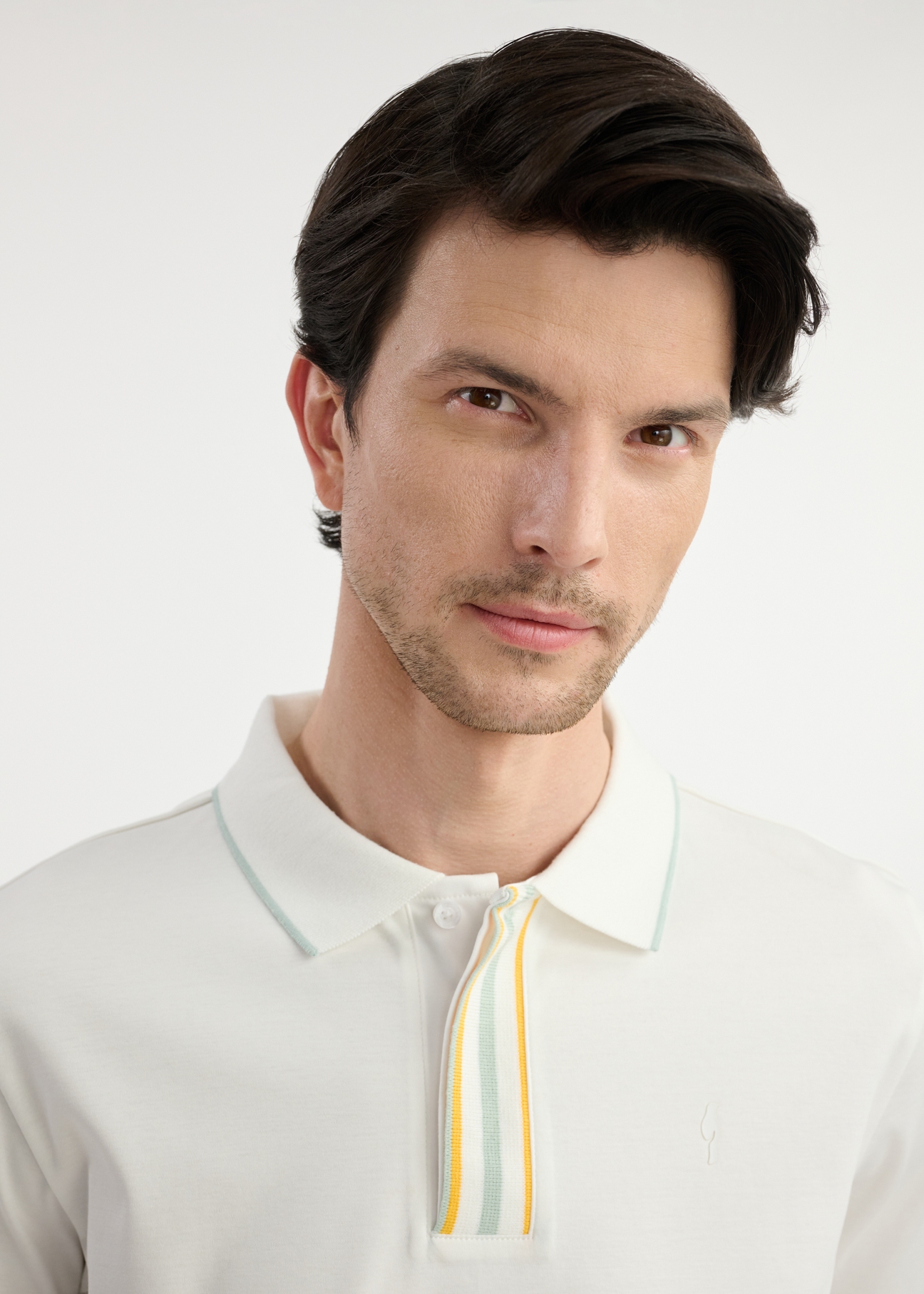 Kremowa koszulka polo męska POLMT-0073-12(W25) - zbliżenie na detal na modelu na białym tle.