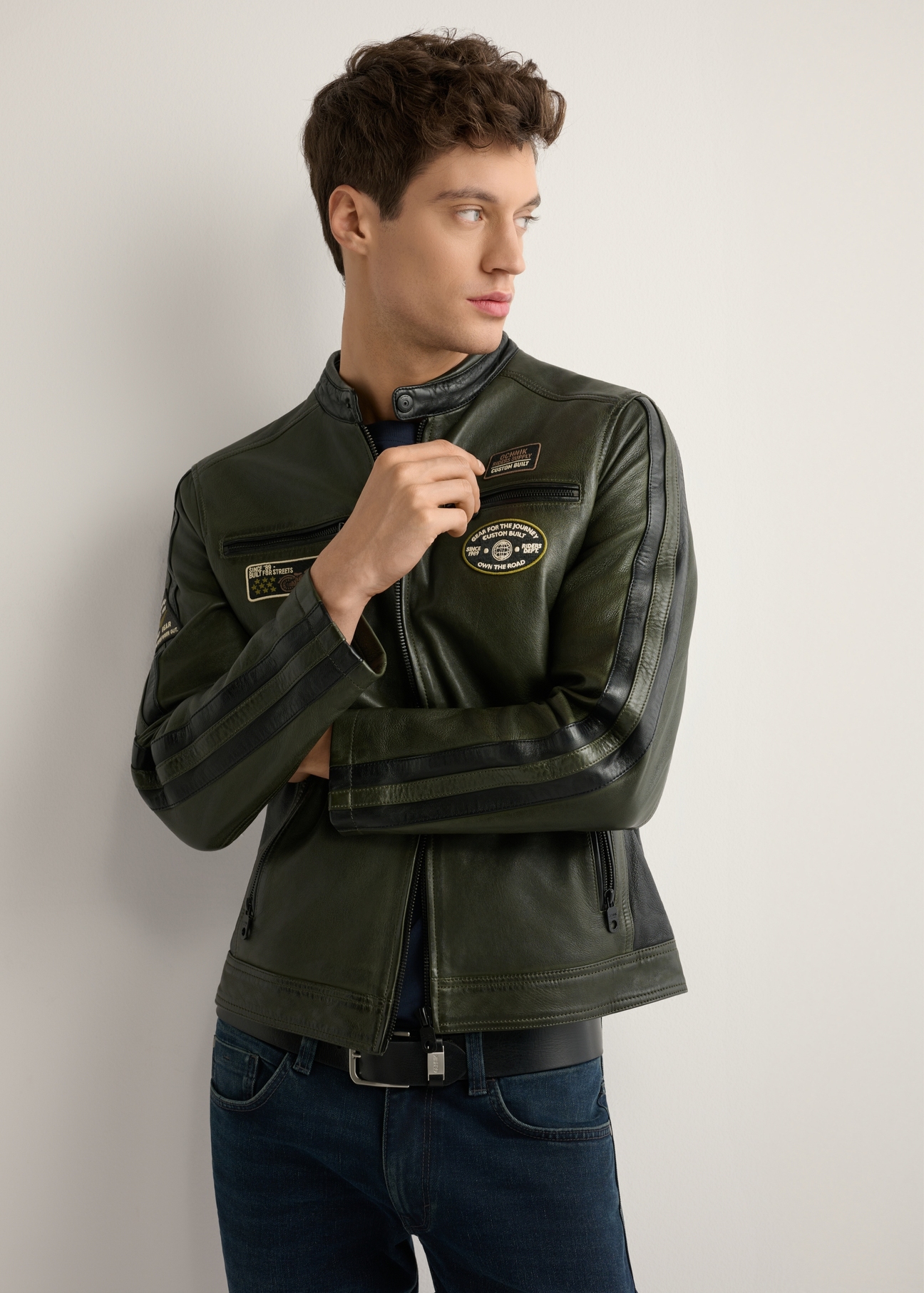 Skórzana kurtka męska w kolorze khaki KURMS-0399-8D(W26) - widok produktu z przodu, na modelu, na jasnym tle. Widoczna połowa sylwetki. 
