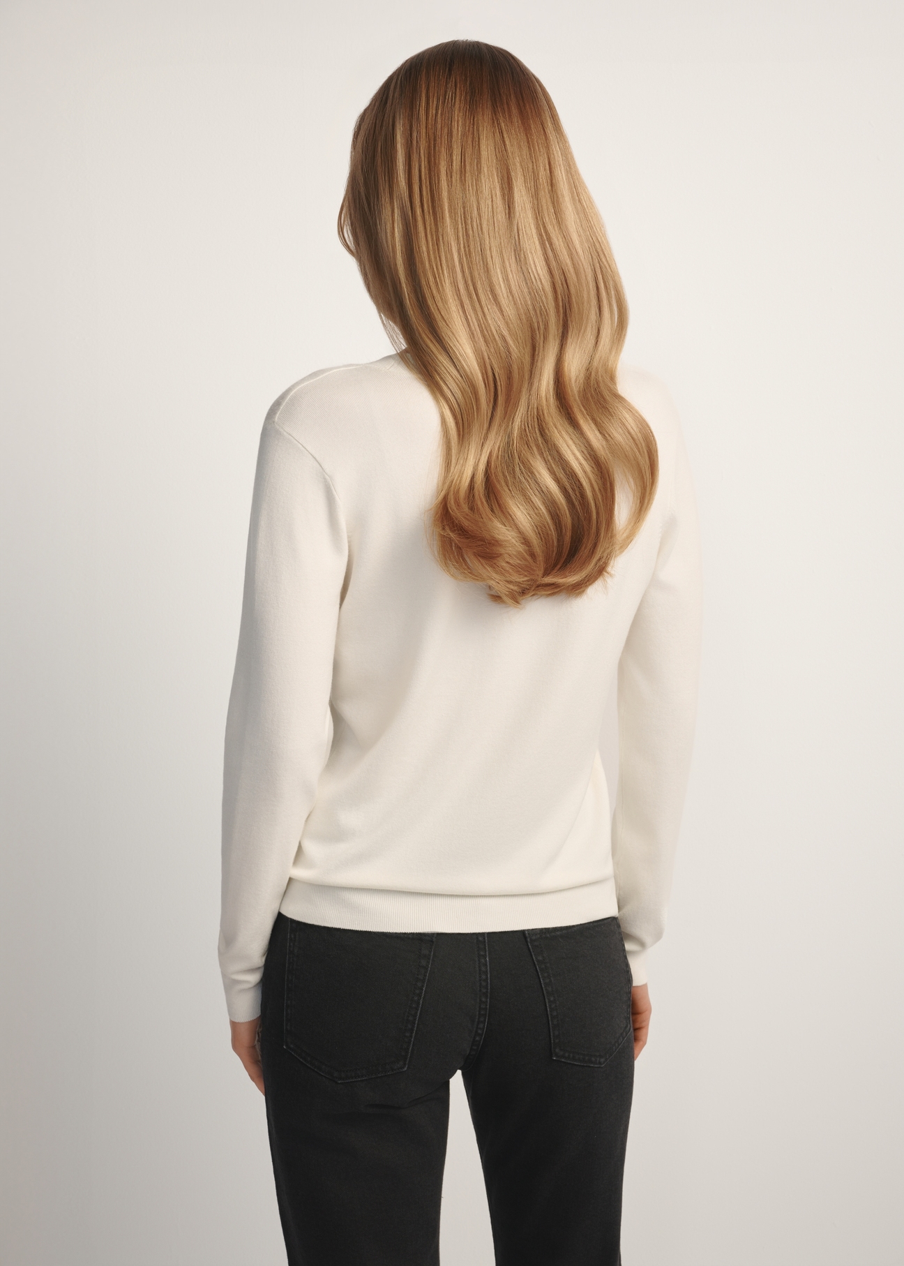 Kremowy sweter z dekoltem V-neck SWEDT-0201-0B(W26), widok produktu z tyłu na modelce. Widoczna połowa sylwetki.