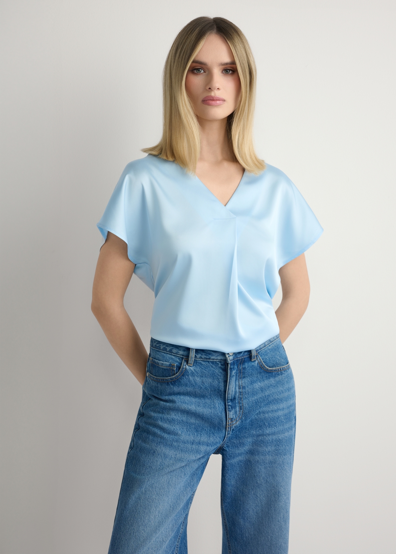 Jasnoniebieska bluzka damska BLUDT-0206-7A(W26), widok produktu z przodu na modelce. Widoczna połowa sylwetki.