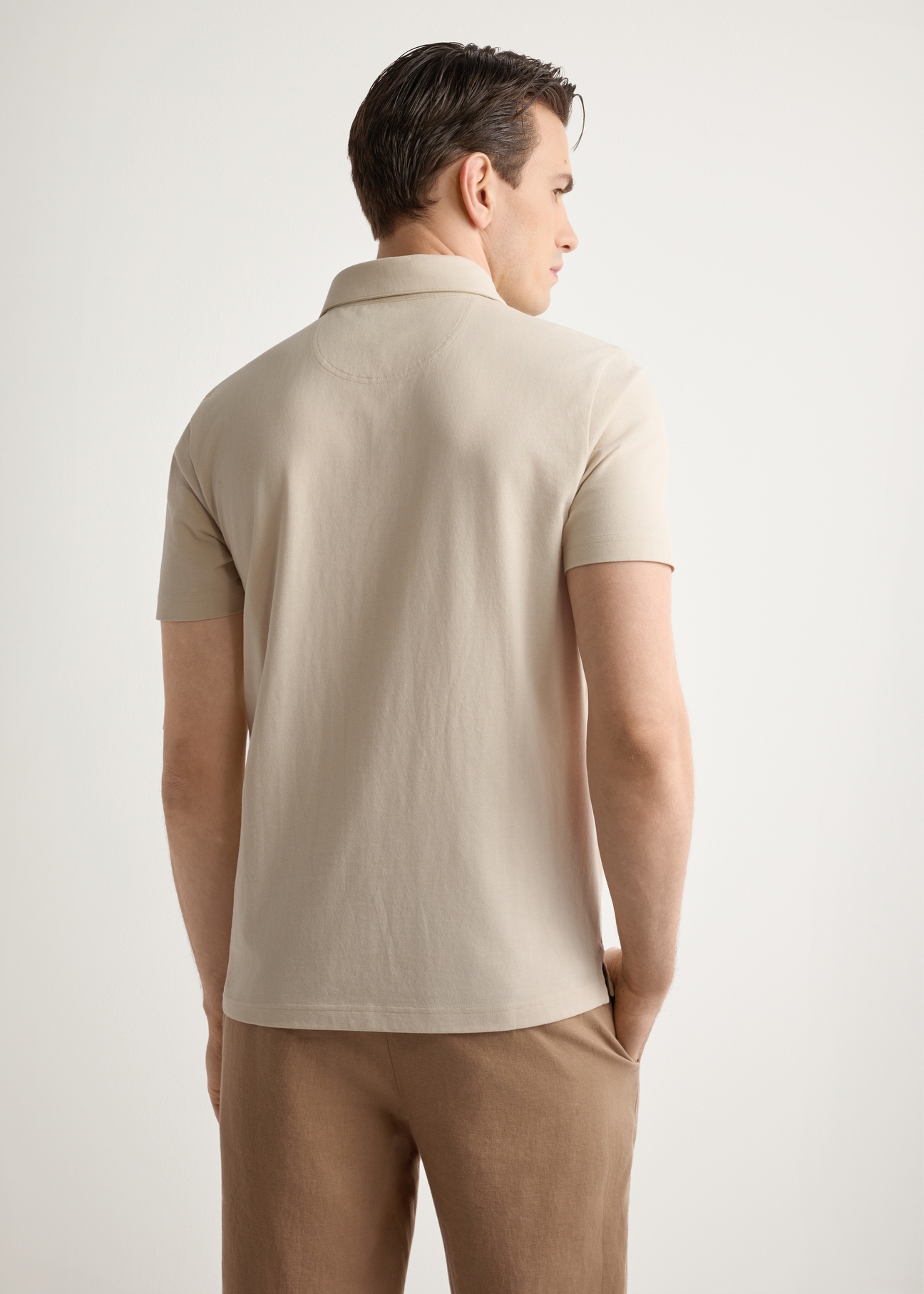 Męska koszulka polo w kolorze jasnego beżu POLMT-0088-1A(W26), widok produktu z tyłu na modelu. Widoczna połowa sylwetki.