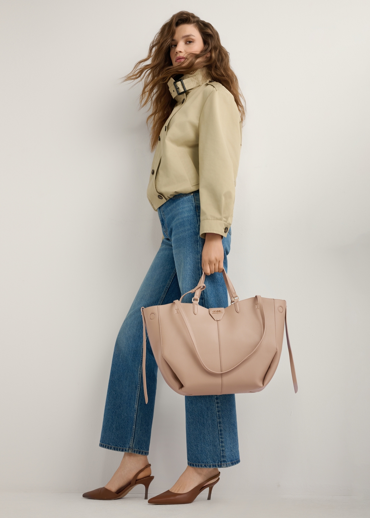 Beżowa duża torebka shopper TOREC-1201-1B(W26), widok produktu w dłoni modelki. Widoczna cała sylwetka.