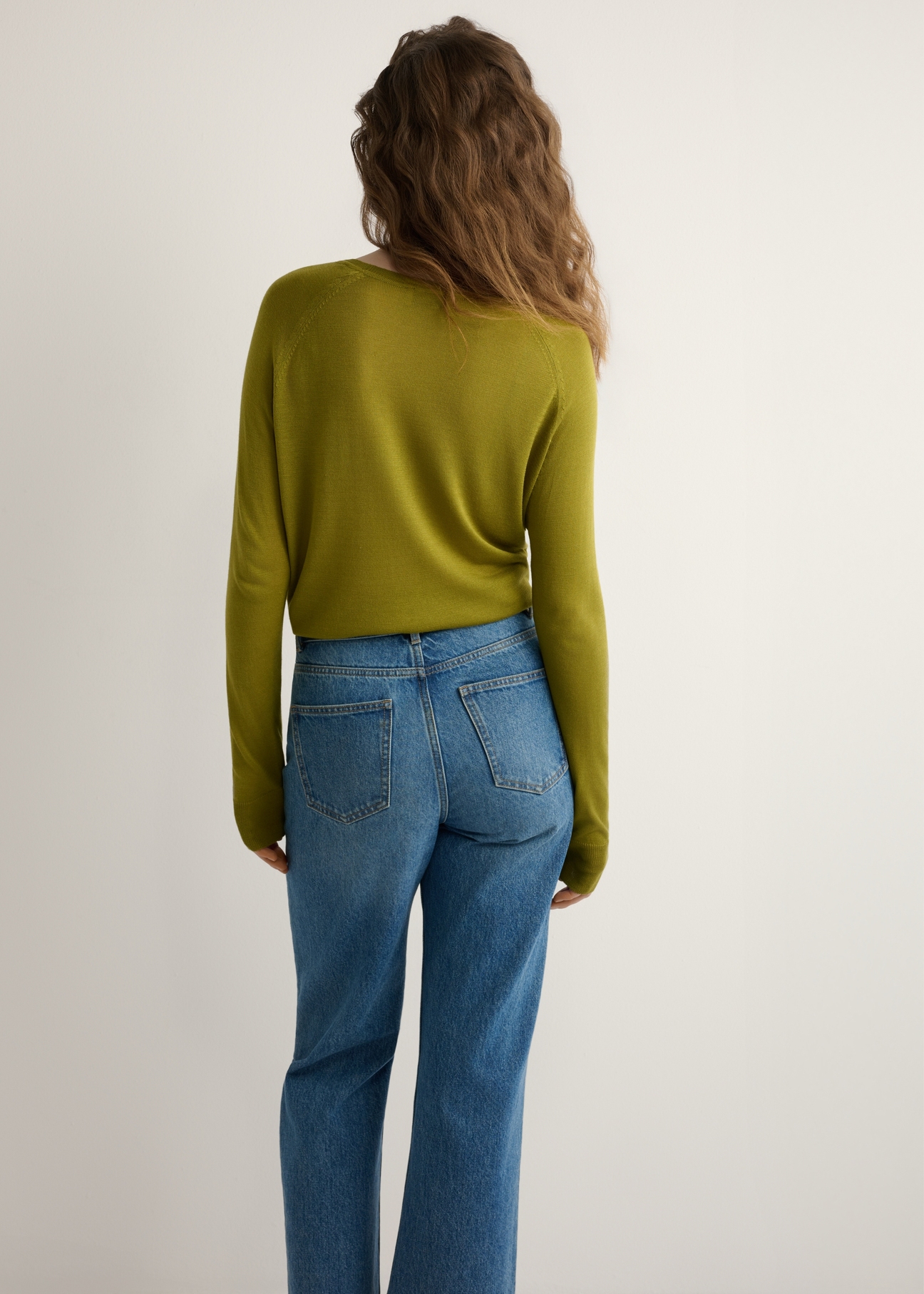 Cienki oliwkowy sweter damski SWEDT-0257-8E(W26), widok produktu z tyłu na modelce. Widoczna połowa sylwetki.