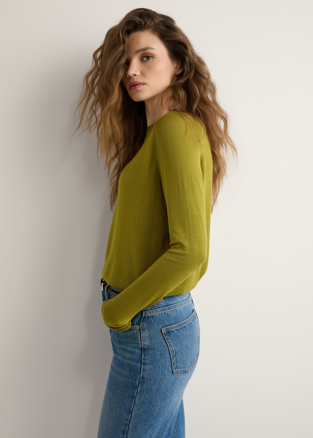 Cienki oliwkowy sweter damski SWEDT-0257-8E(W26), widok produktu z boku na modelce. Widoczna połowa sylwetki.
