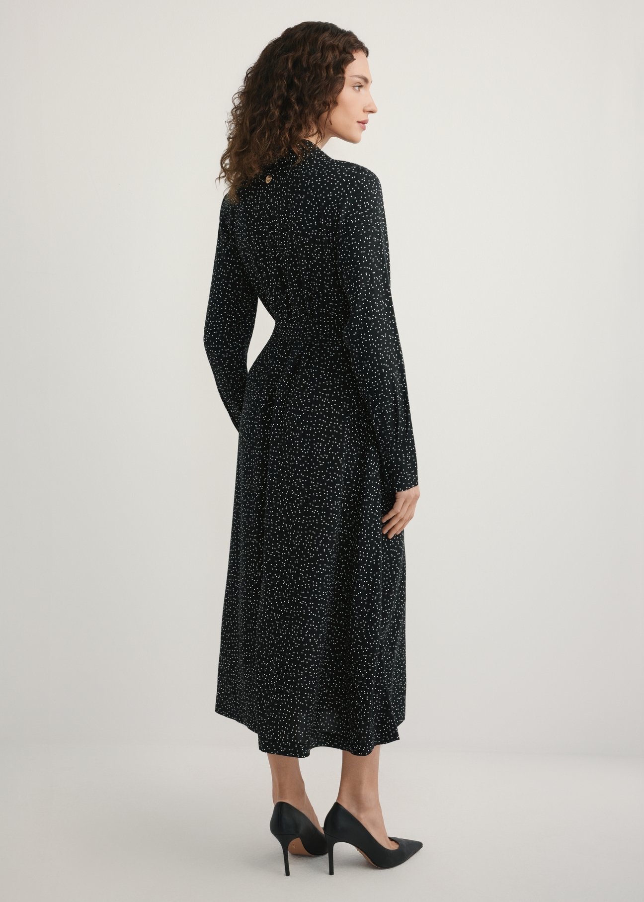 Czarna sukienka w kropki SUKDT-0258-9P(W26), widok produktu z tyłu na modelce. Widoczna cała sylwetka.
