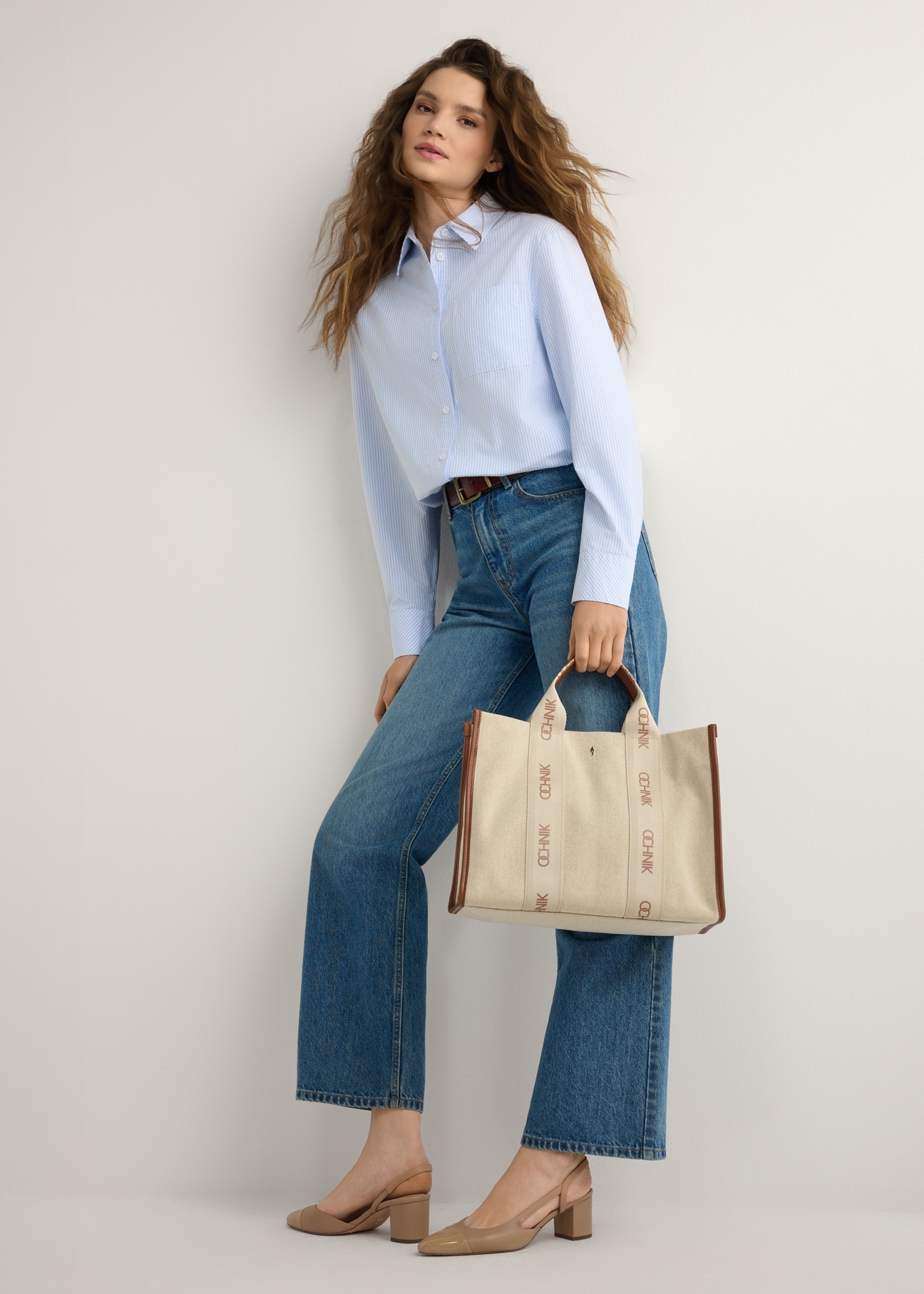 Beżowa damska torebka typu tote bag TOREN-0288A-1E(W26), widok produktu w dłoni modelki. Widoczna cała sylwetka.