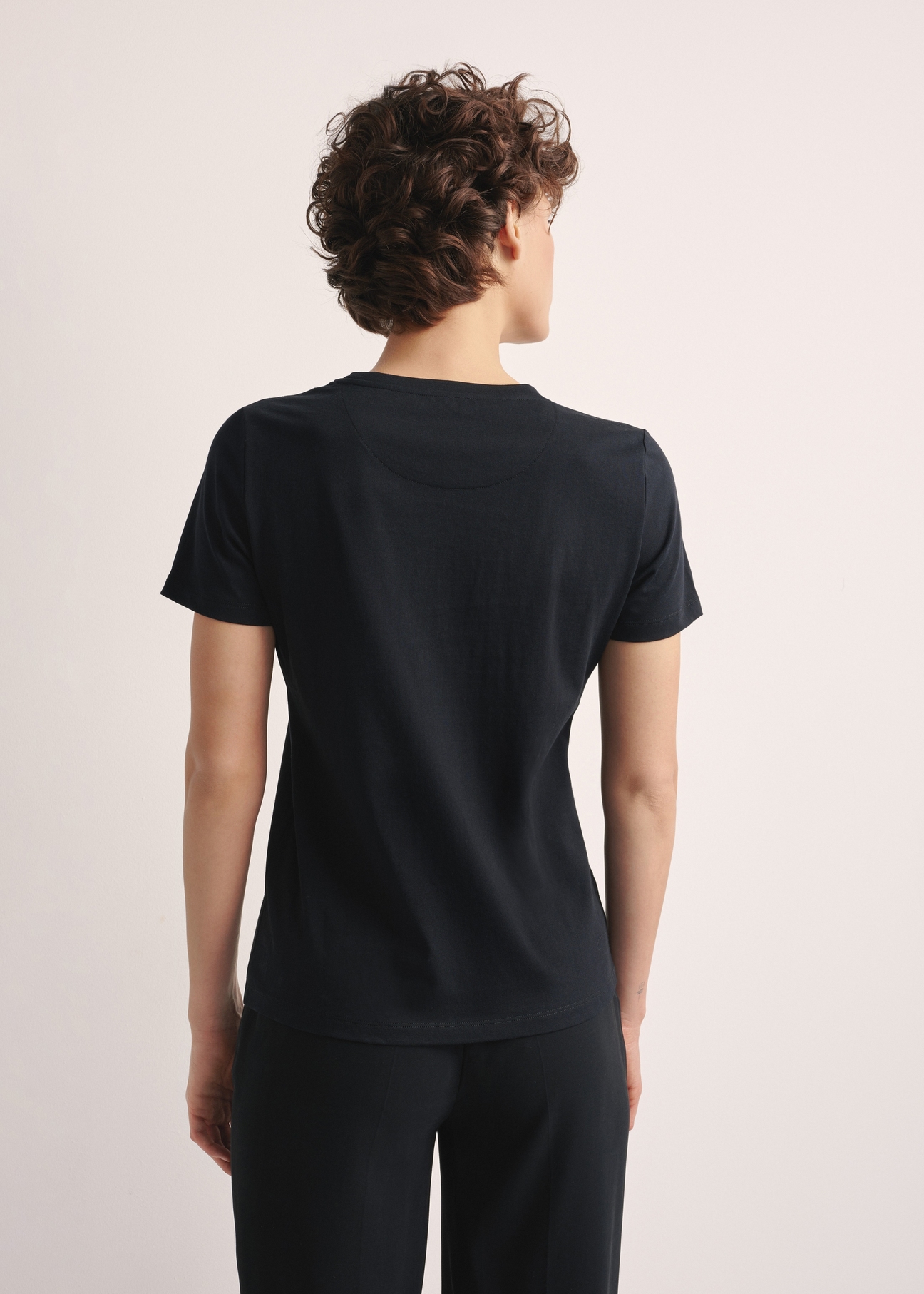 Czarny T-shirt damski z logo TSHDT-0148-99(Z25), widok produktu z tyłu na modelce. Widoczna połowa sylwetki.