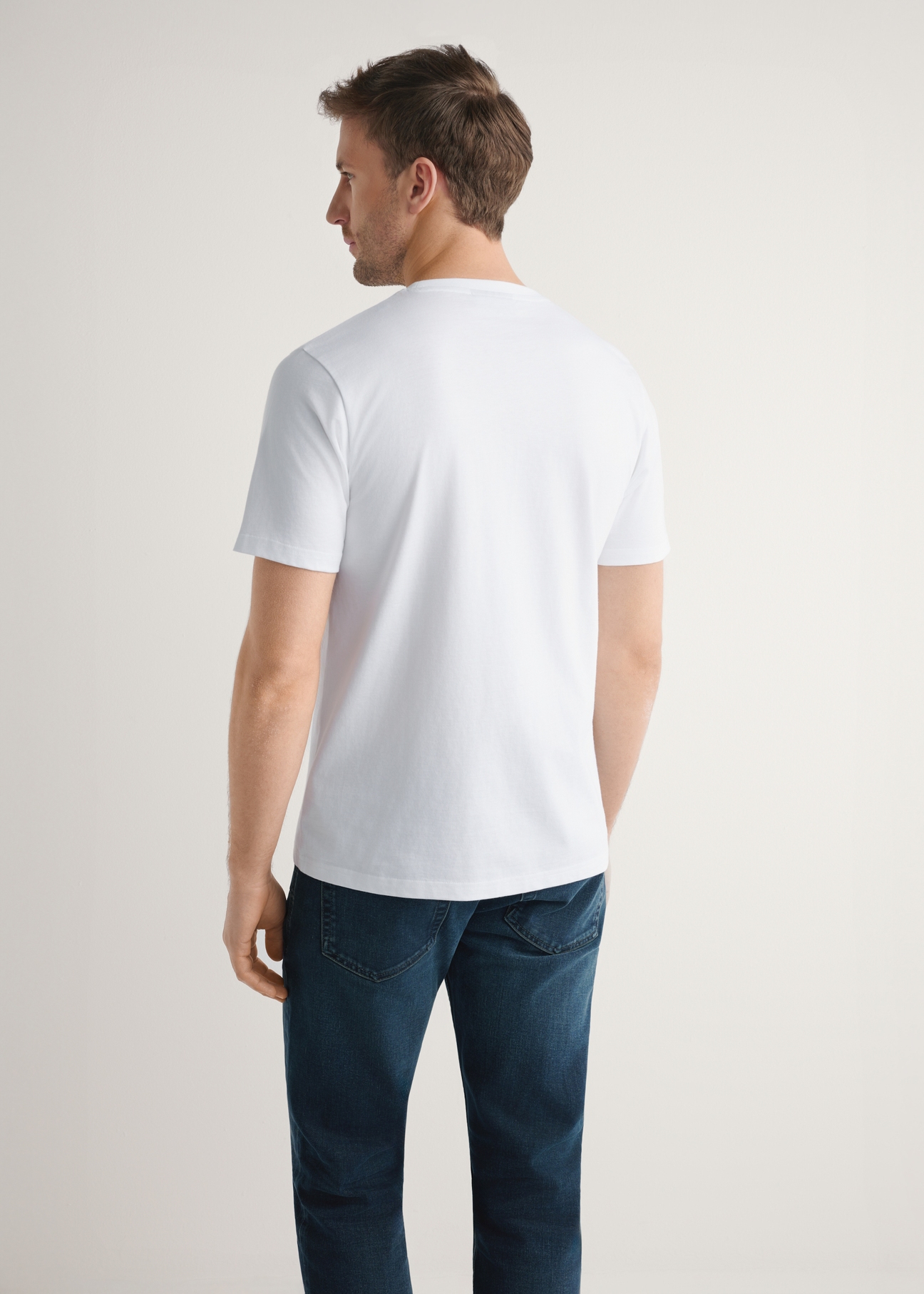 Biały bawełniany t-shirt męski TSHMT-0144-0A(W26) - widok produktu z tyłu na modelu, na jasnym tle. Widoczna sylwetka do połowy.