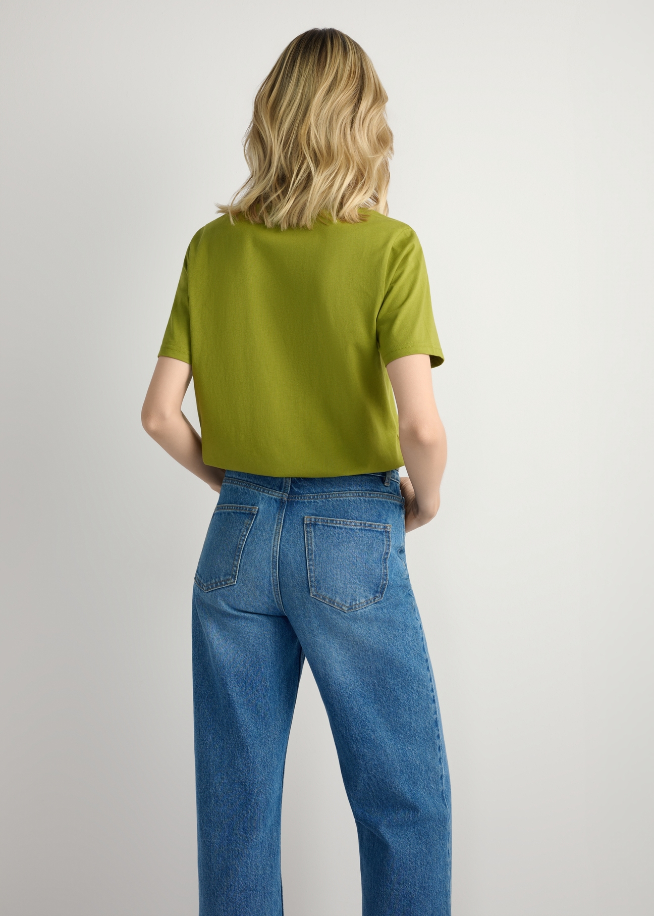 Oliwkowy T-shirt damski basic TSHDT-0120-8E(W26), widok produktu z tyłu na modelce. Widoczna połowa sylwetki.