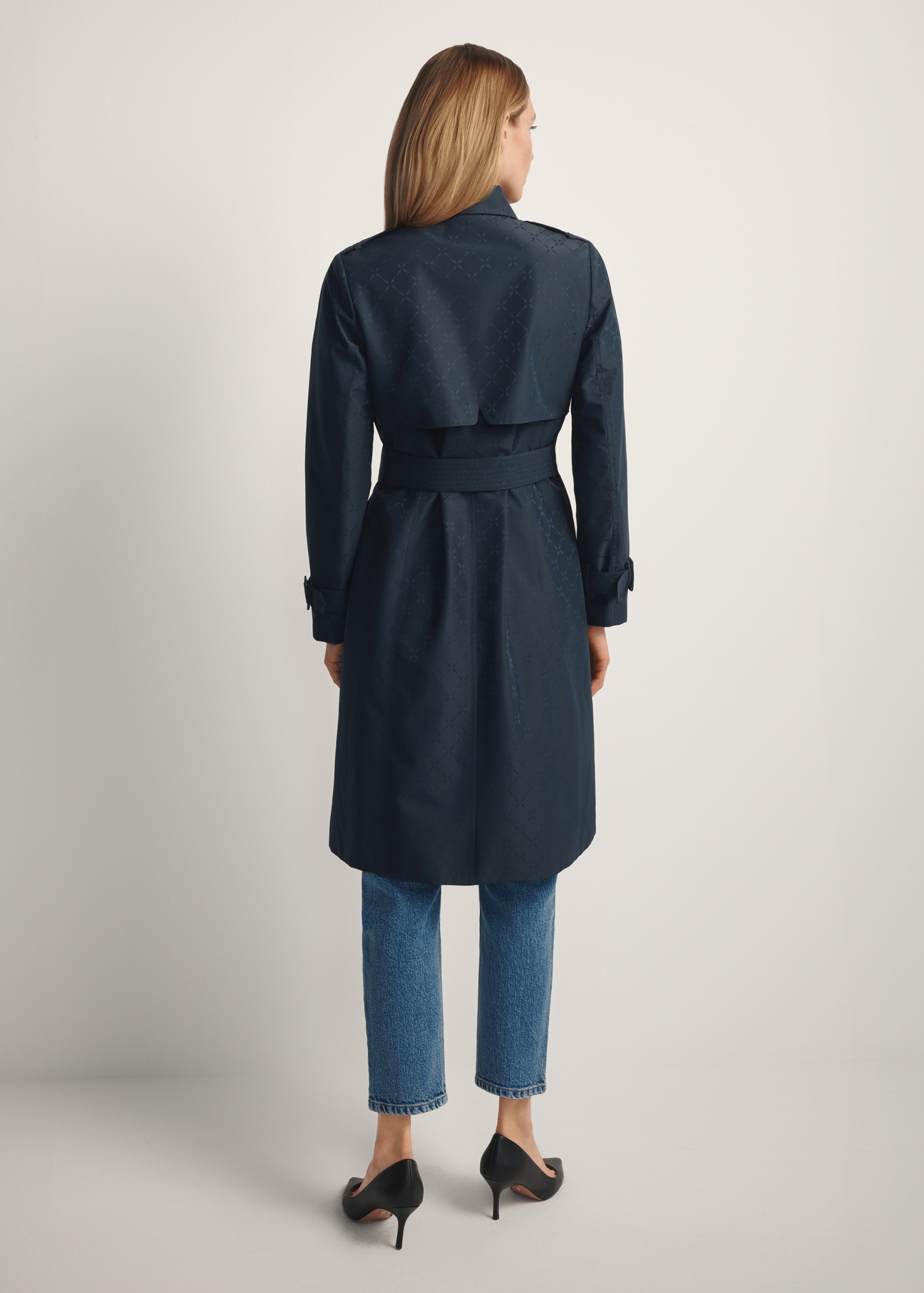 Granatowy płaszcz damski z monogramem KURDT-0651-7E(W26), widok produktu z tyłu na modelce. Widoczna cała sylwetka.