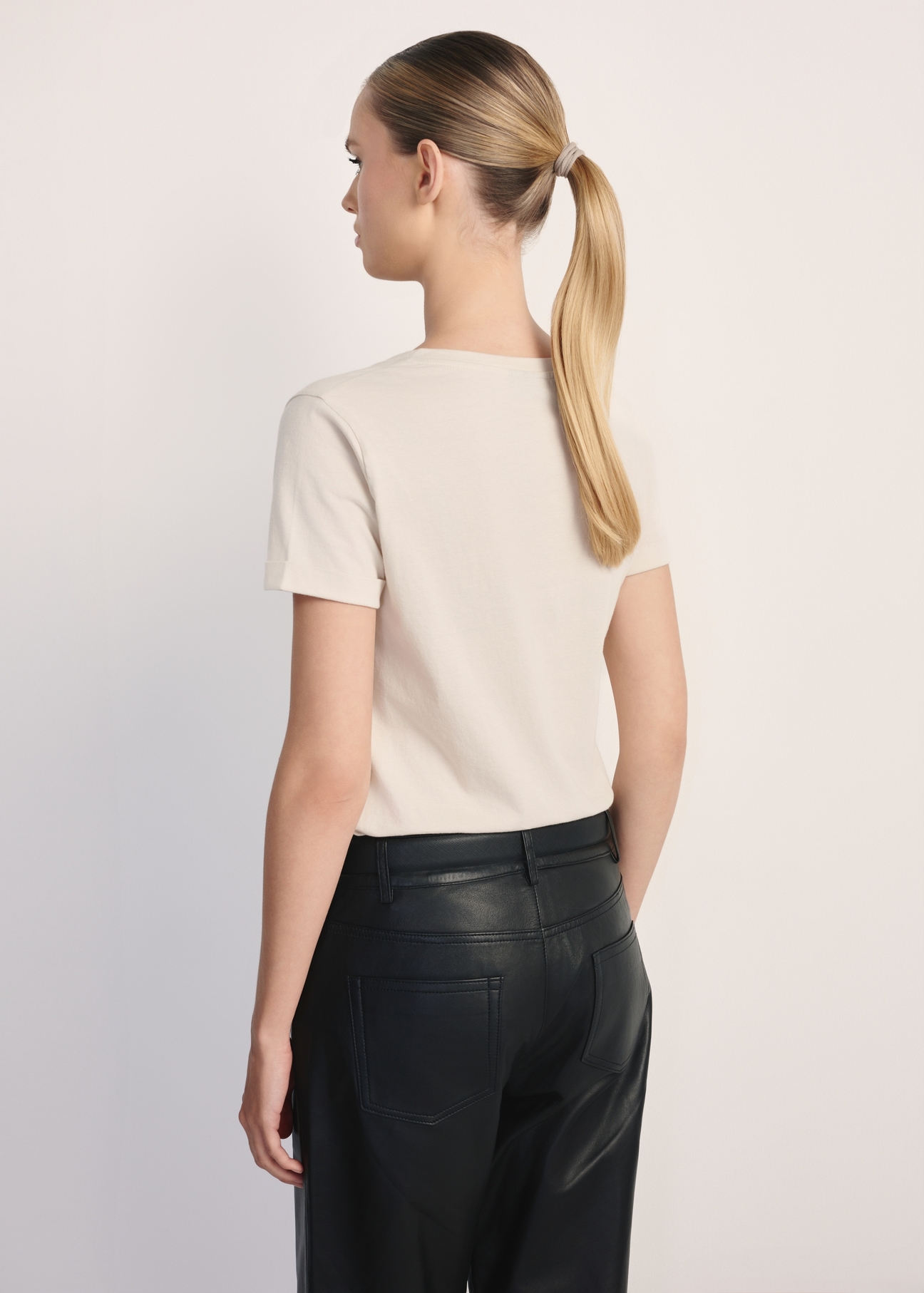 Beżowy T-shirt damski w serek TSHDT-0118A-80(Z25), widok produktu z tyłu na modelce. Widoczna połowa sylwetki.