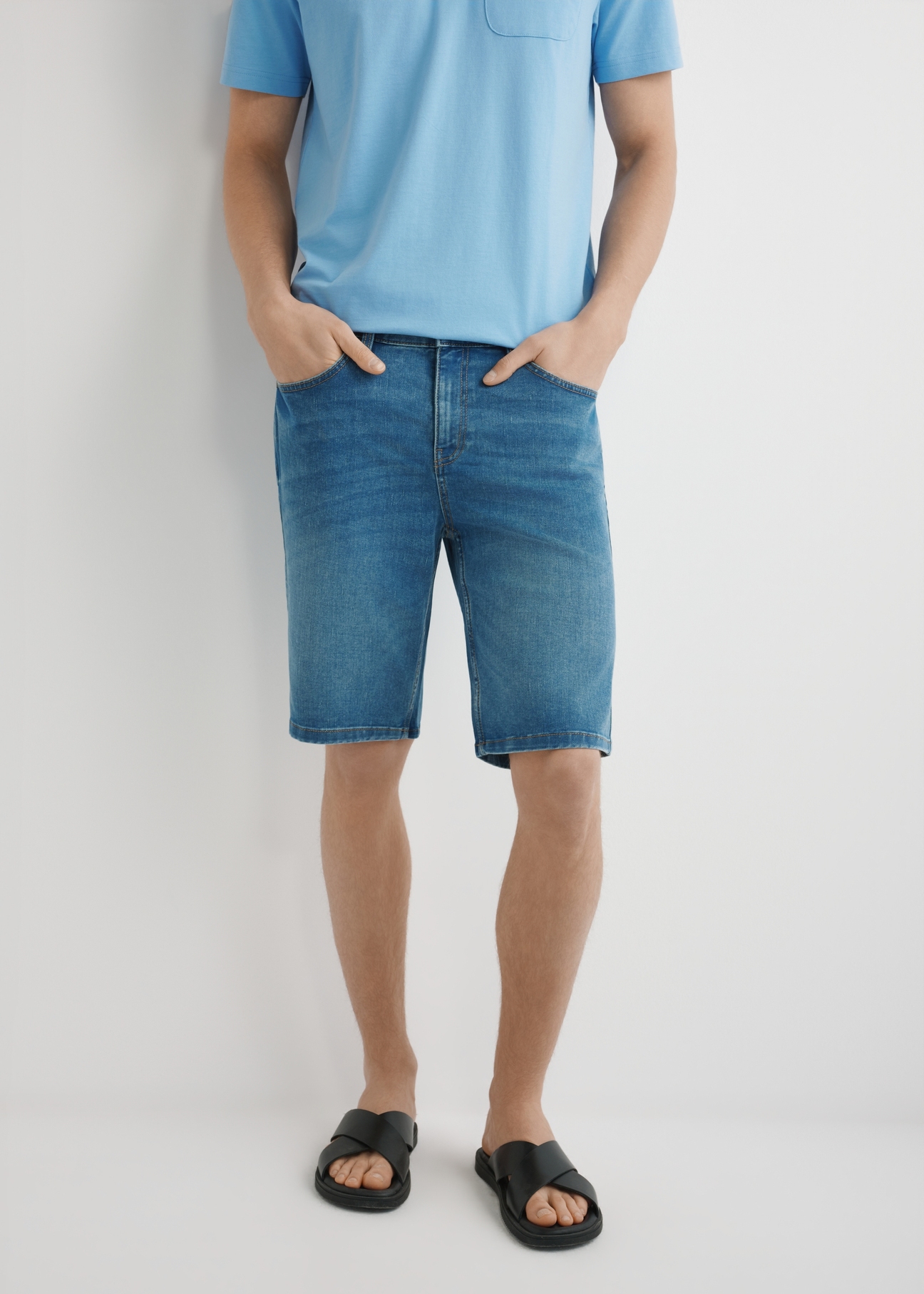 Niebieskie jeansowe szorty męskie SZOMT-0036-7H(W26) - widok produktu z przodu, na modelu, na jasnym tle. Widodczna połowa sylwetki.