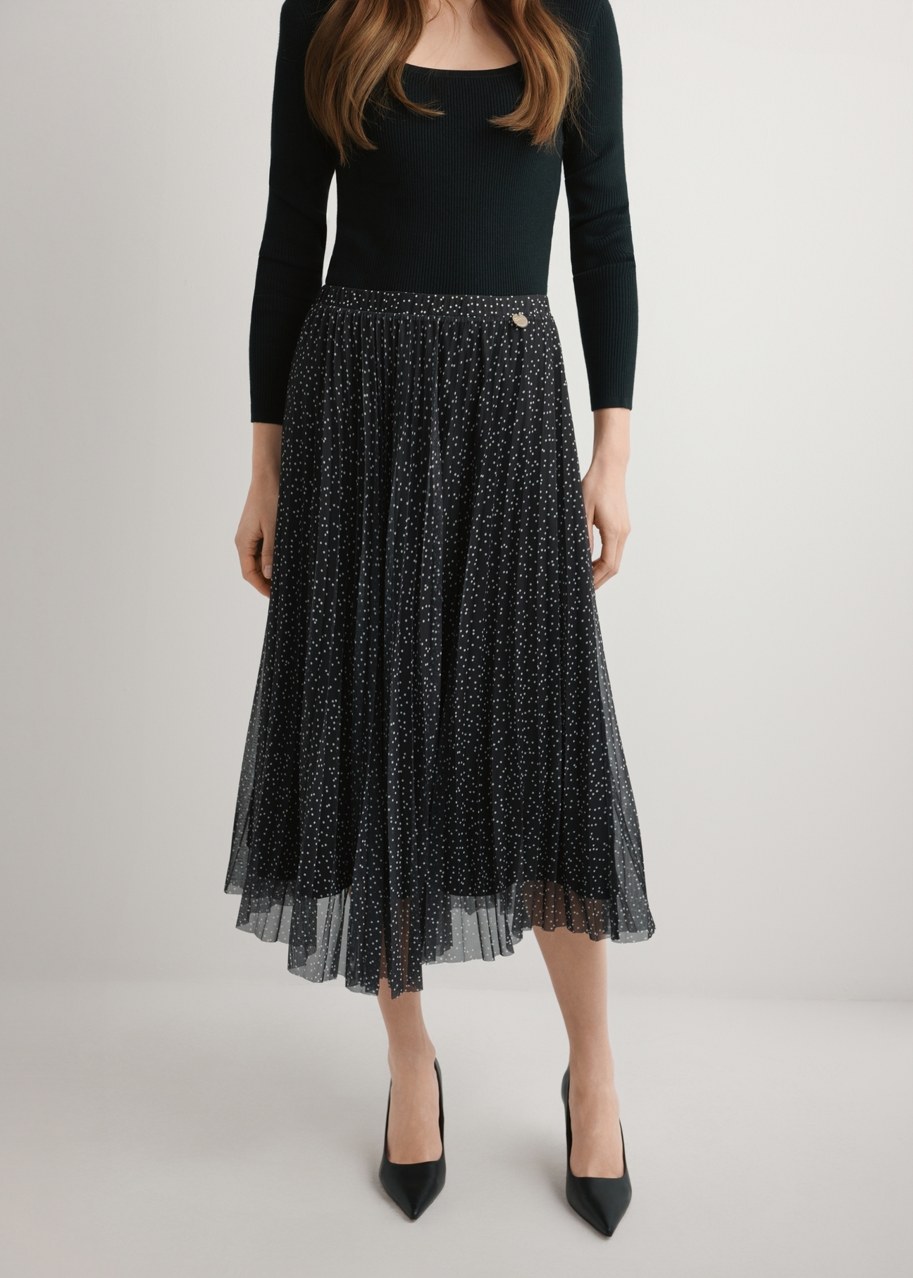 Spódnica plisowana midi w kropki SPCDT-0110-9P(W26), widok produktu od przodu na modelce, widoczna połowa sylwetki.