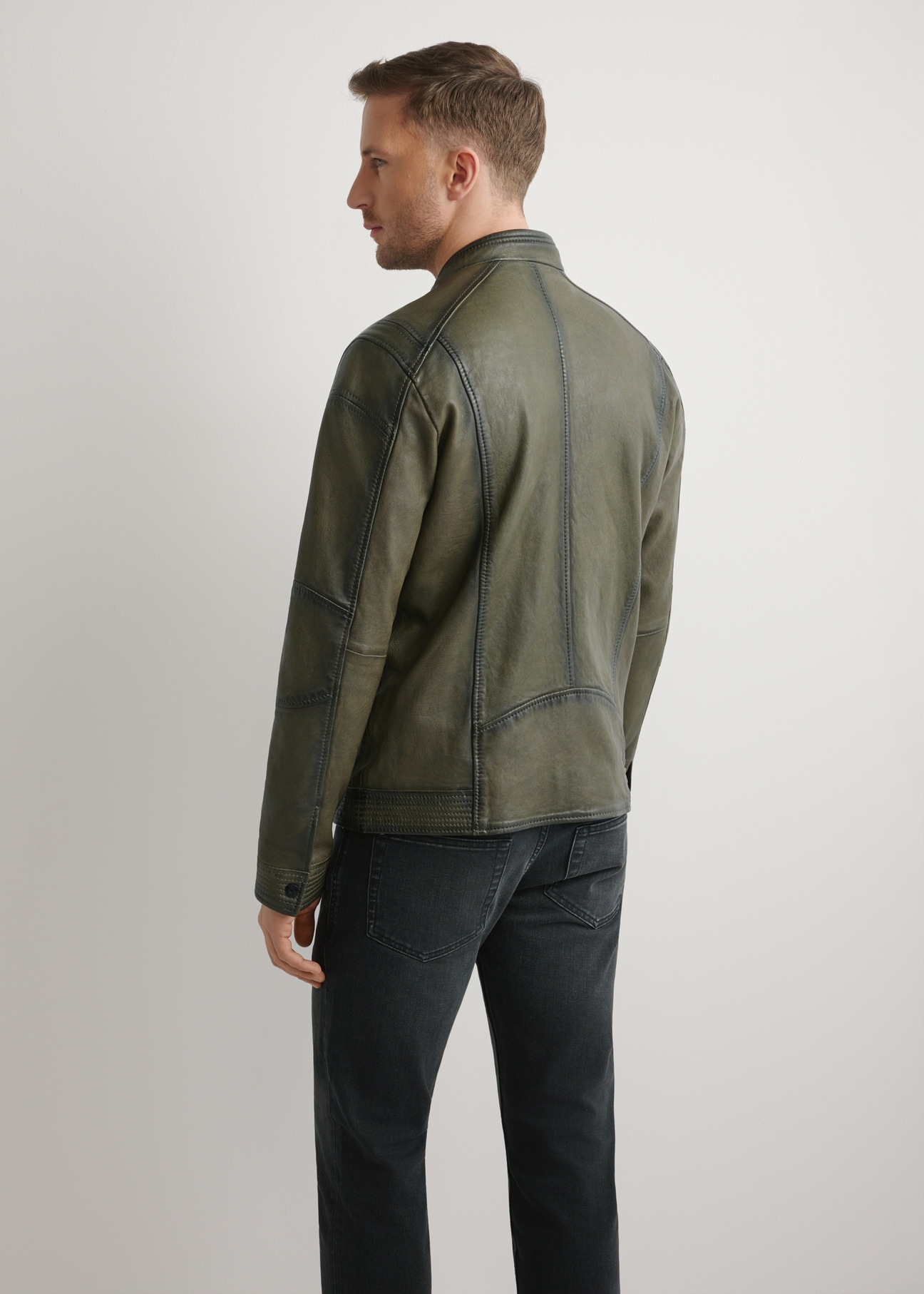 Skórzana kurtka męska w kolorze khaki KURMS-0403-8D(W26) - widok produktu z tyłu, na modelu, na jasnym tle. Widoczna sylwetka do kolan.