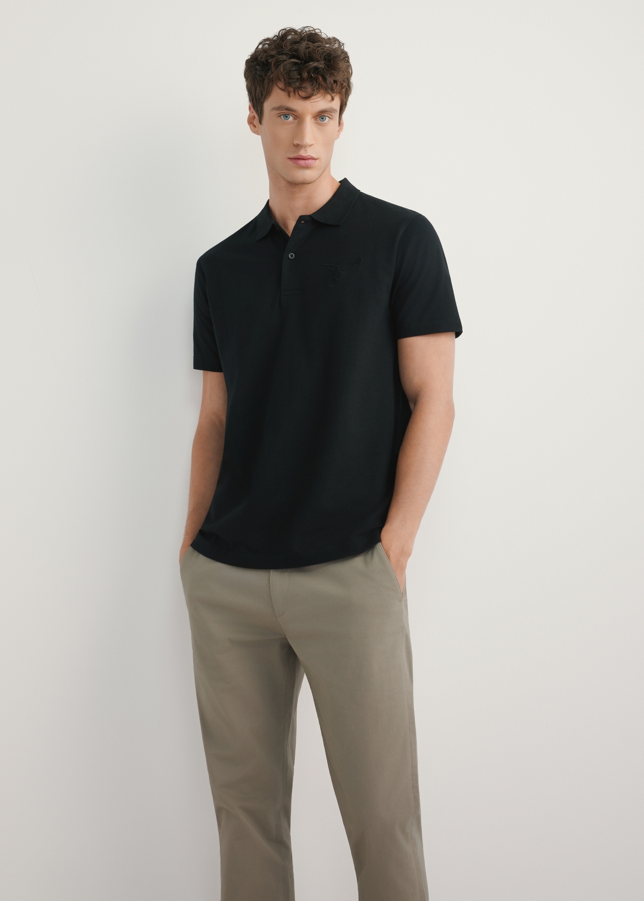 Czarna koszulka polo męska POLMT-0084-99(W26) - widok produktu z przodu, na modelu, na jasnym tle. Widoczna cała sylwetka.