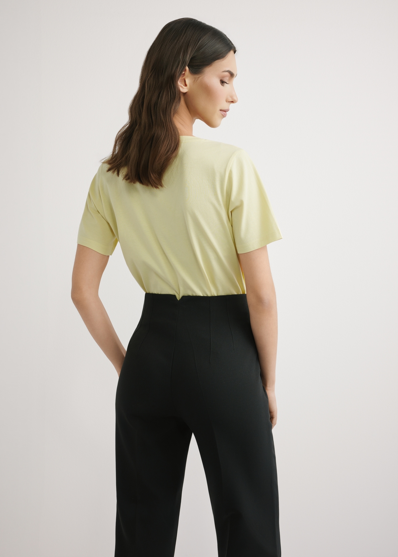 Jasnożółty T-shirt damski basic TSHDT-0120-2A(W26), widok produktu z tyłu na modelce. Widoczna połowa sylwetki.