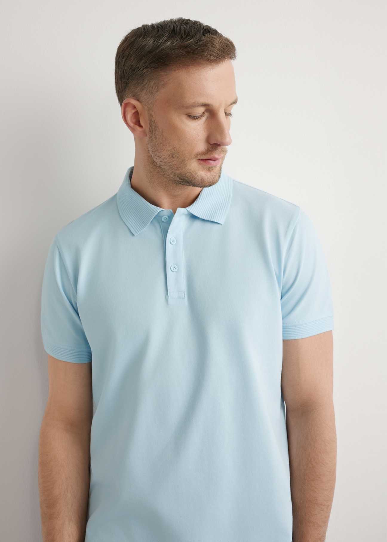Błękitna koszulka polo męska POLMT-0089-7A(W26), widok produktu z przodu na modelu. Widoczna połowa sylwetki.