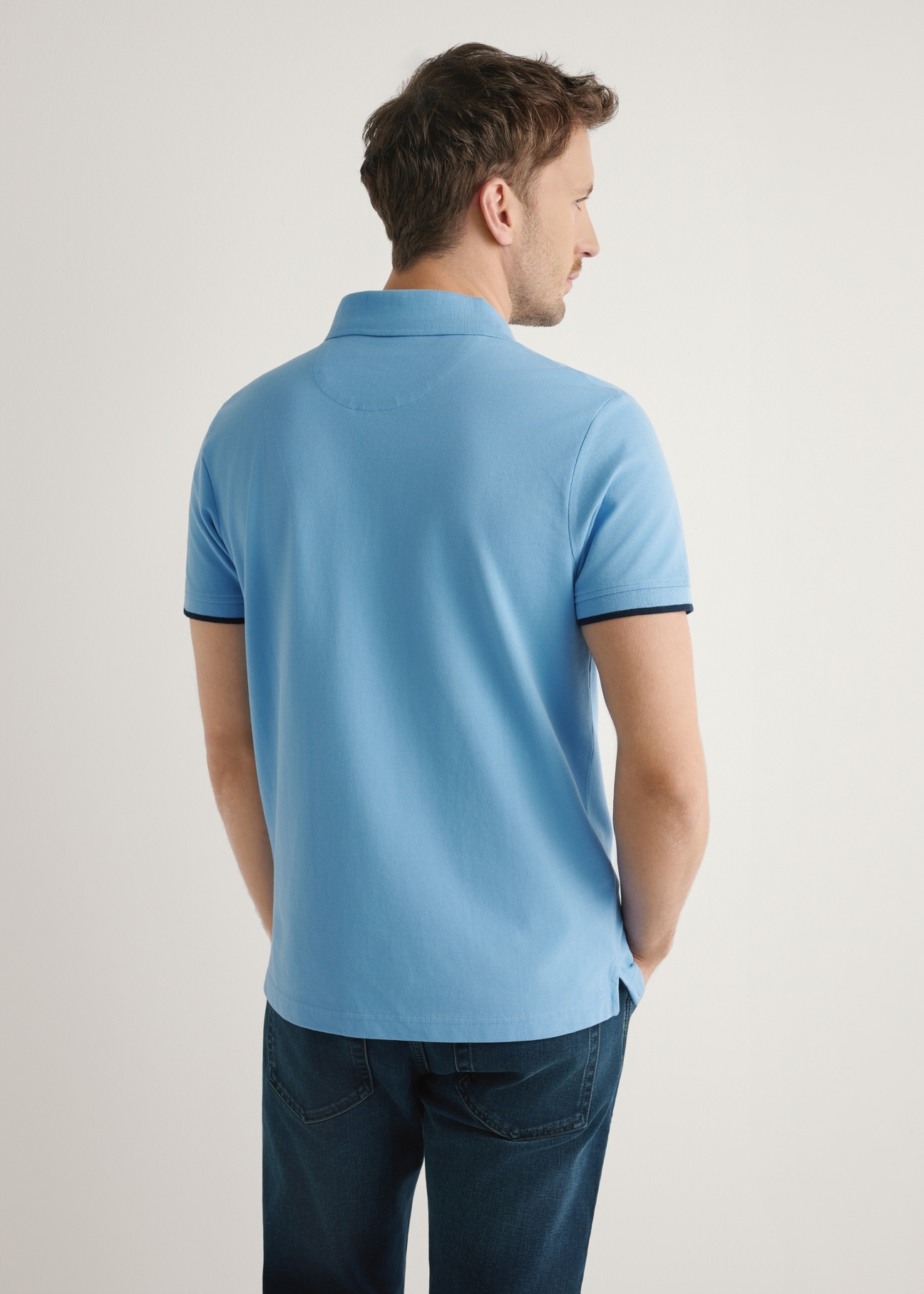 Niebieska koszulka polo z bawełny POLMT-0045B-7B(W26), widok produktu z tyłu na modelu. Widoczna połowa sylwetki.