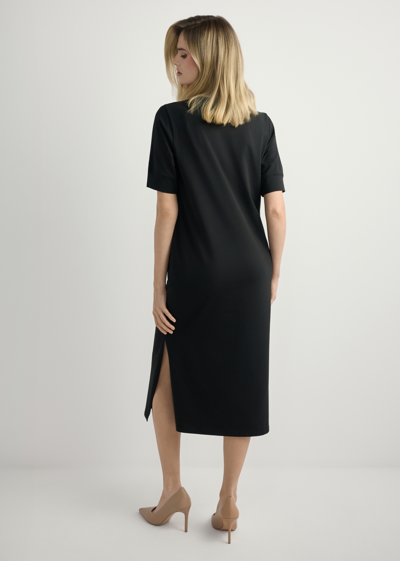 Czarna bawełniana sukienka midi SUKDT-0256-99(W26) - widok produktu z tyłu, na modelce, na jasnym tle. Widoczna cała sylwetka. 