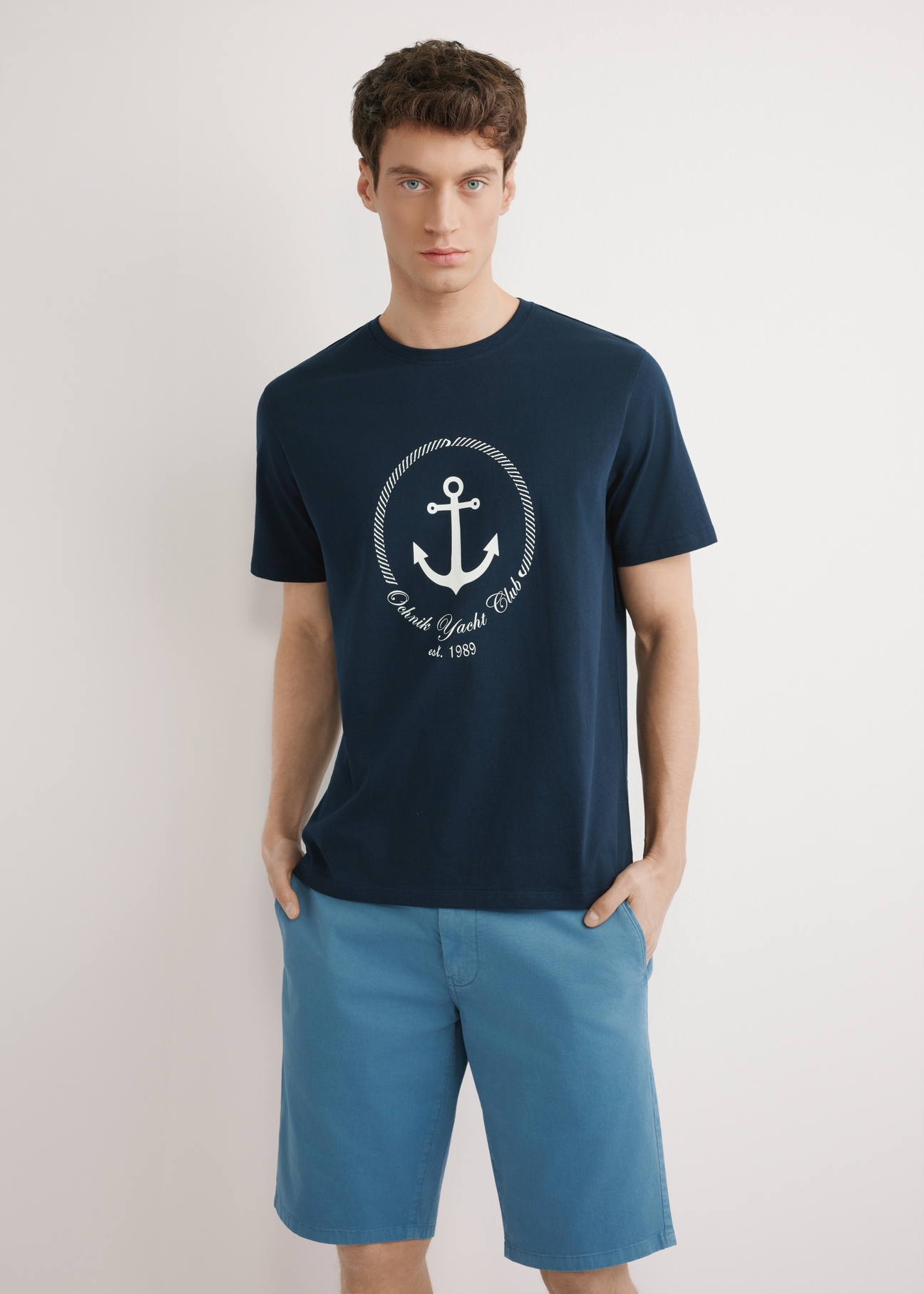 Granatowy T-shirt męski z nadrukiem TSHMT-0147-7E(W26), widok produktu z przodu, na modelu, na jasnym tle. Widoczna połowa sylwetki.  
