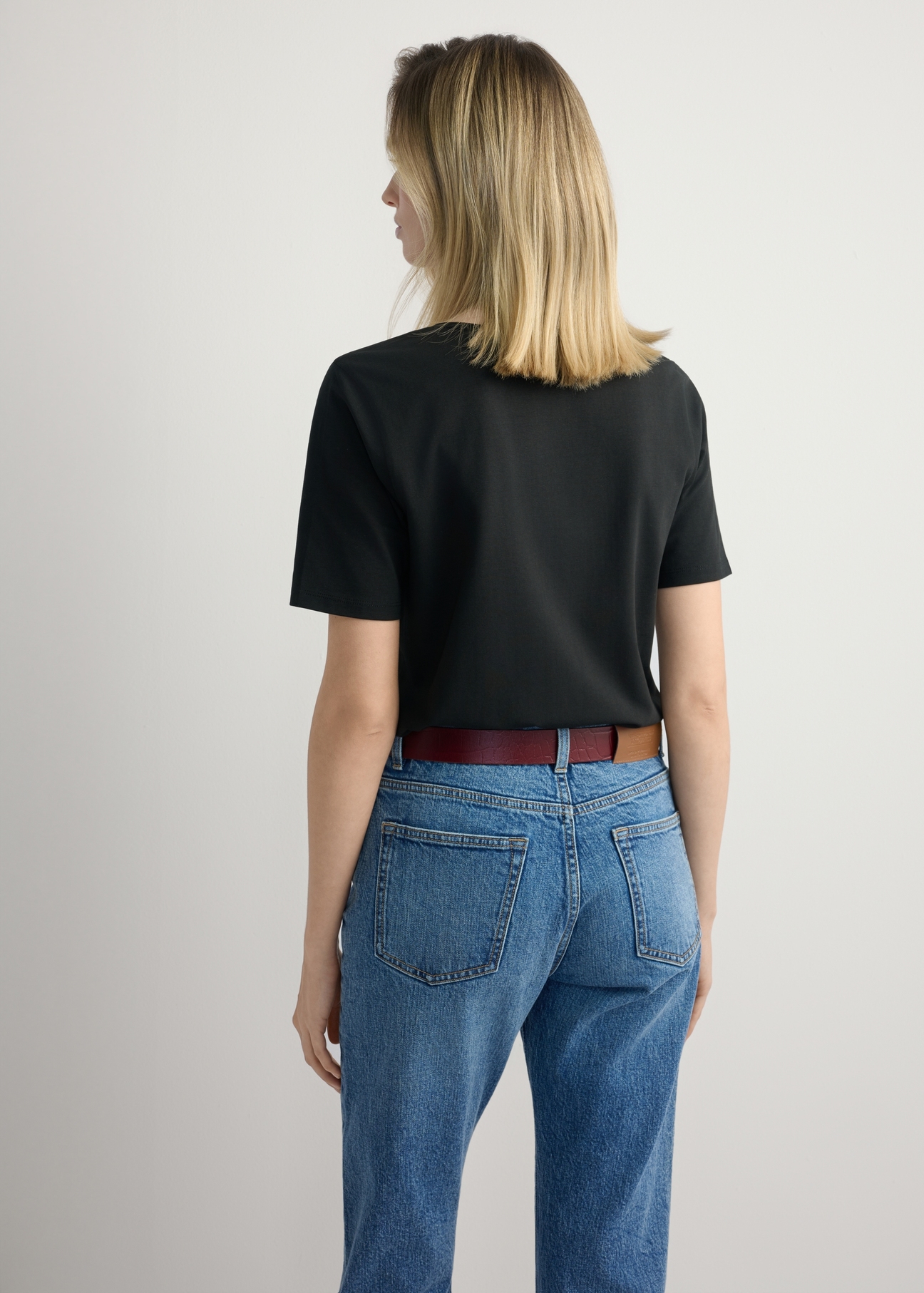 Czarny bawełniany T-shirt damski TSHDT-0151-99(W26), widok produktu z tyłu na modelce. Widoczna połowa sylwetki.