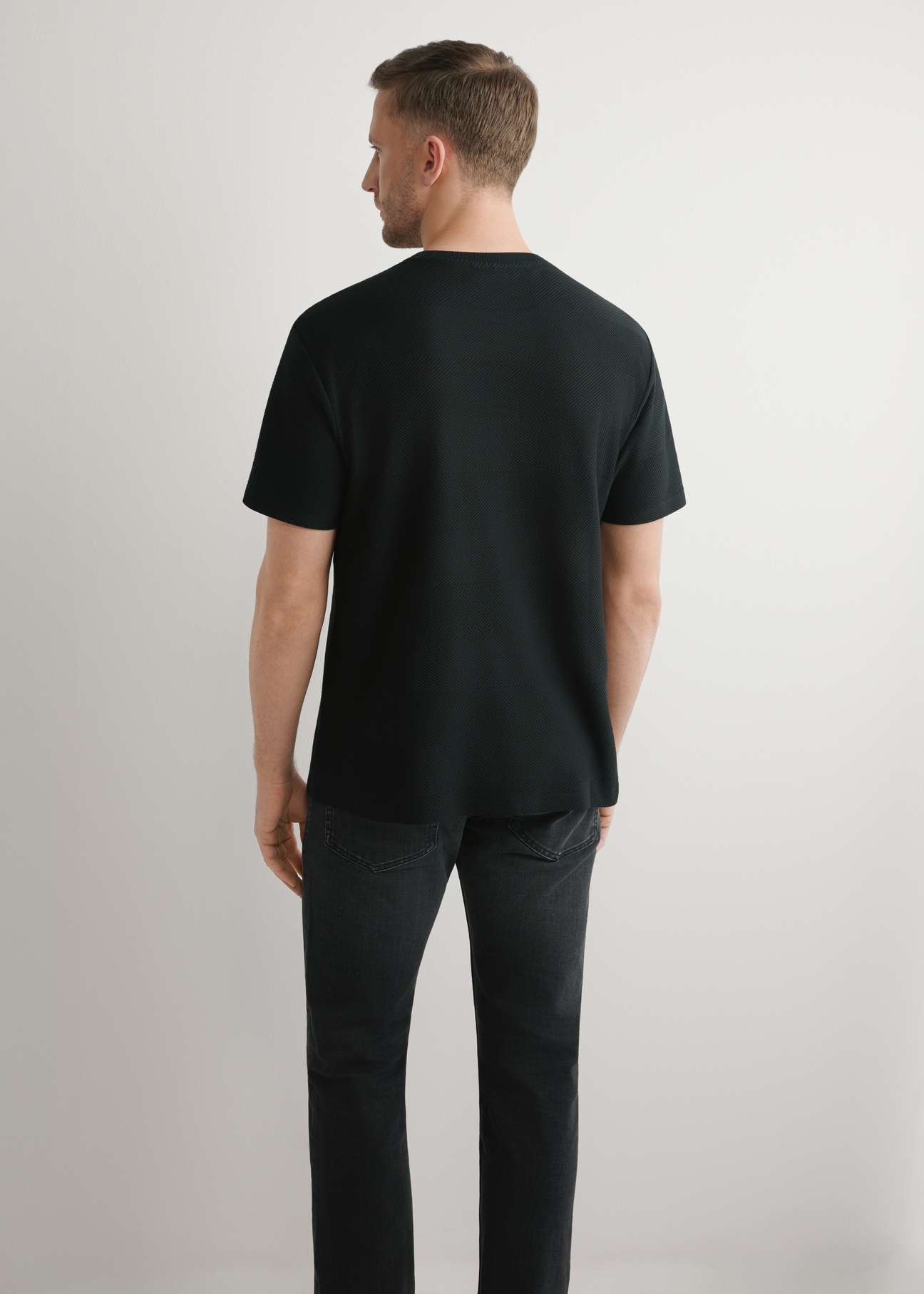 Czarny prążkowany t-shirt męski TSHMT-0142-99(W26), widok produktu z tyłu na modelu. Widoczna połowa sylwetki.
