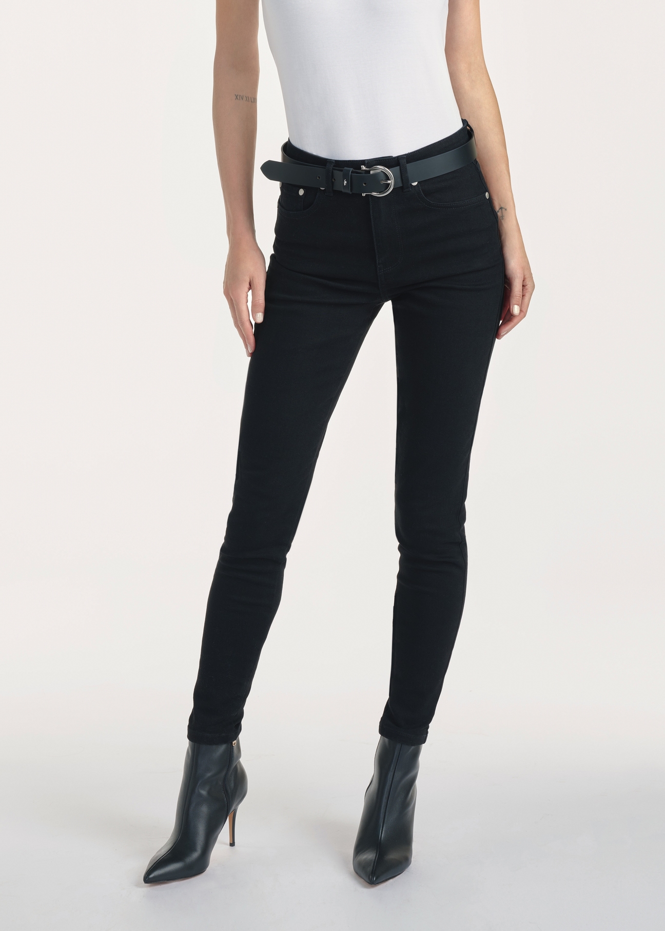 Czarne jeansowe spodnie damskie JEADT-0010A-99(Z25), produkt widoczny z przodu na modelce, widoczne pół sylwetki.