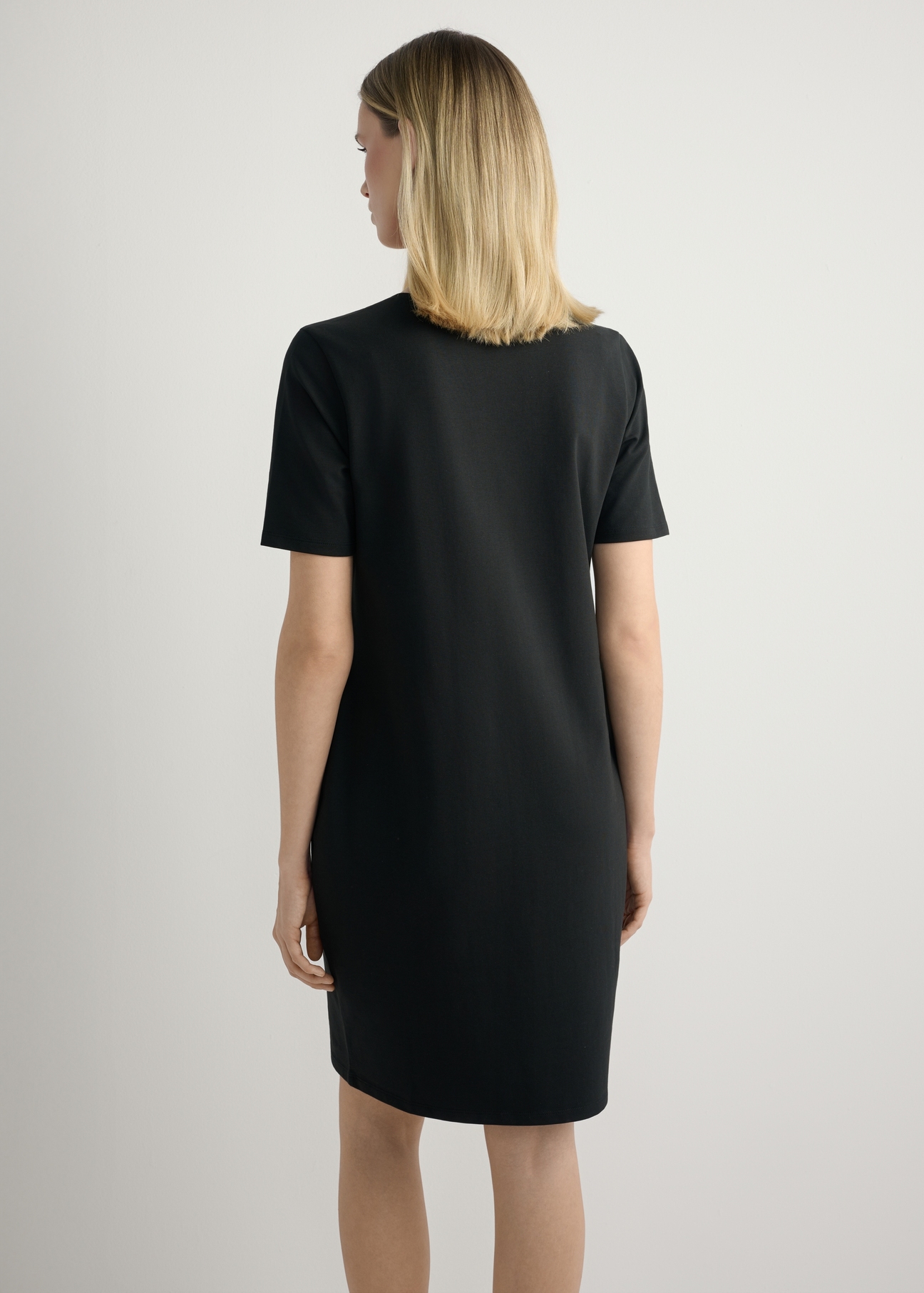 Czarna bawełniana sukienka SUKDT-0185A-99(W26), widok produktu z tyłu na modelce. Widoczna połowa sylwetki.