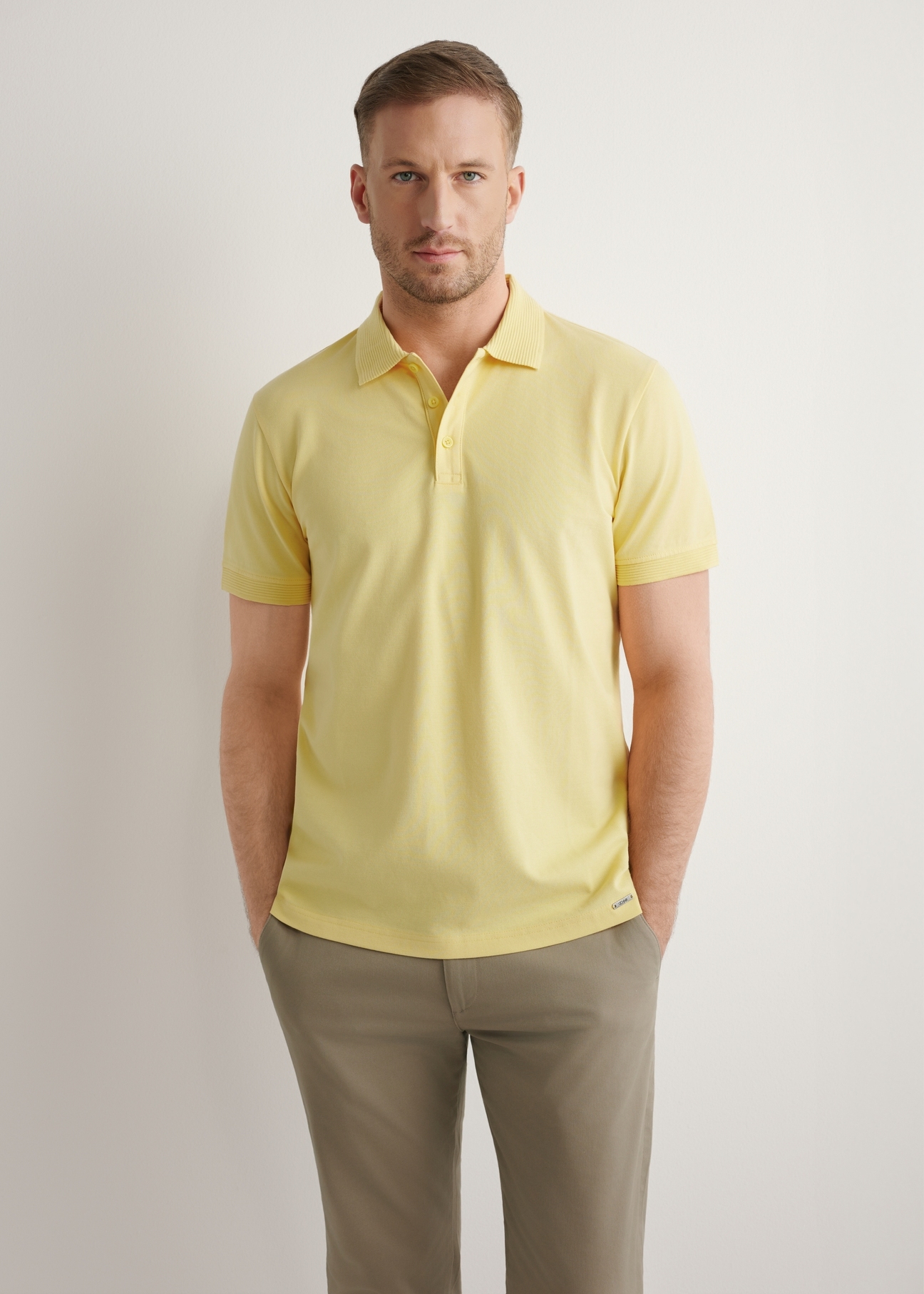 Żółta koszulka polo męska POLMT-0089-2B(W26), widok produktu z przodu na modelu. Widoczna połowa sylwetki.
