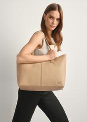 Beżowa torebka damska shopper TOREC-1208-1A(W26), widok produktu od przodu na modelce, widoczna połowa sylwetki.