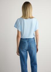 Jasnoniebieska bluzka damska BLUDT-0206-7A(W26), widok produktu z tyłu na modelce. Widoczna połowa sylwetki.