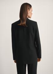 Marynarka damska w kolorze czarnym ZAKDT-0031A-99(W26), widok produktu z tyłu na modelce. Widoczna połowa sylwetki.