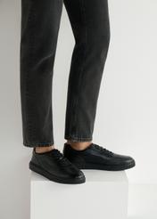 Czarne skórzane sportowe buty męskie BUTYM-0484-99(W25), widok produktu od boku na modelu, widoczna połowa sylwetki.