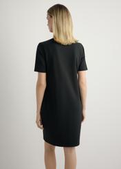 Czarna bawełniana sukienka SUKDT-0185A-99(W26), widok produktu z tyłu na modelce. Widoczna połowa sylwetki.